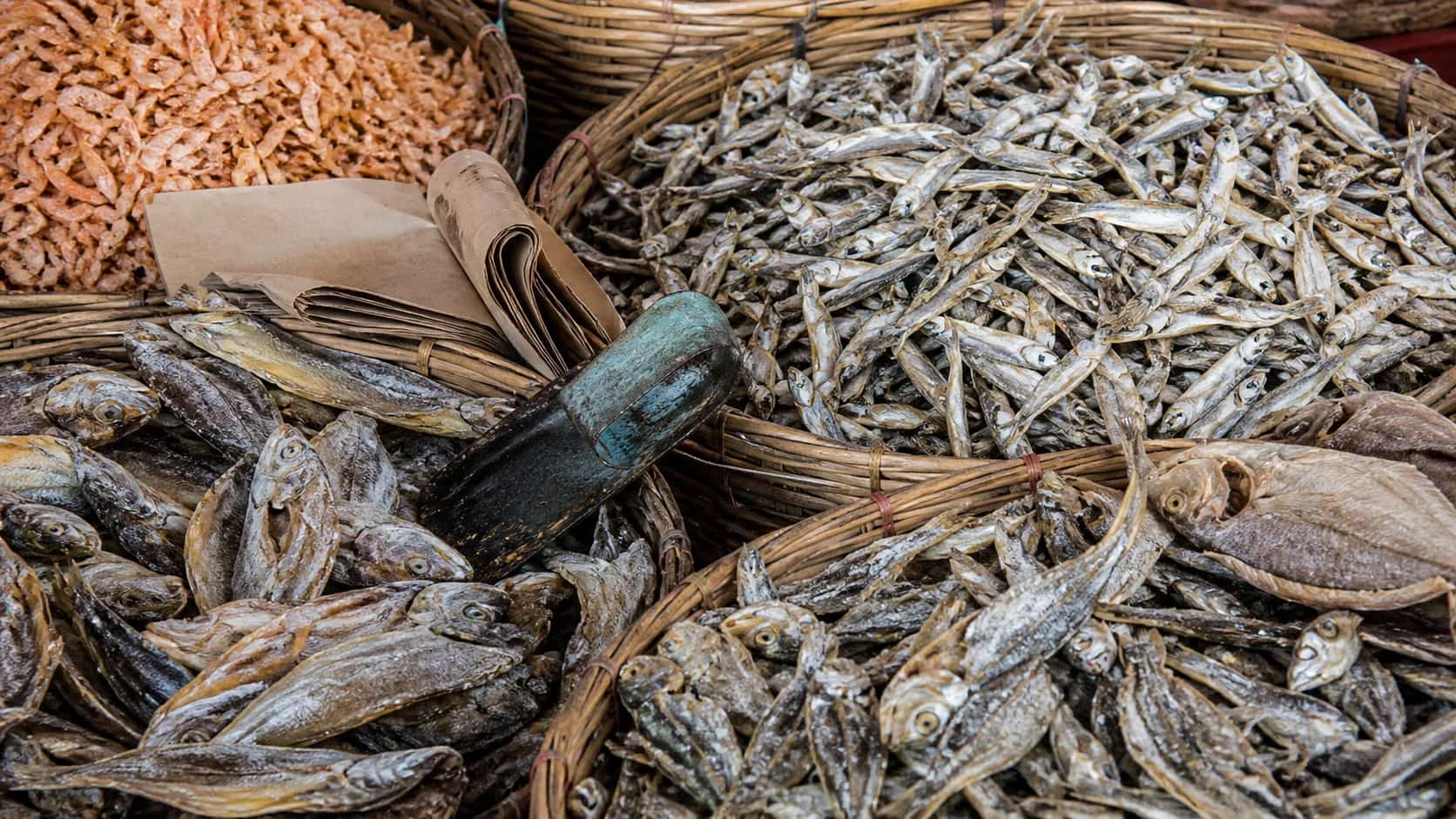 An assortment of traditional sun-dried fish and prawns in coastal market baskets